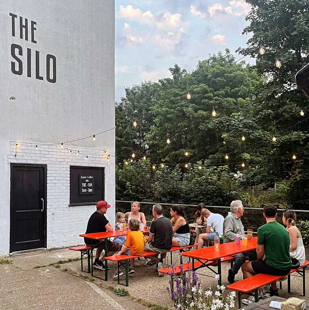 The Silo cafe exterior beside the River Waveney, with string lights over outdoor tables